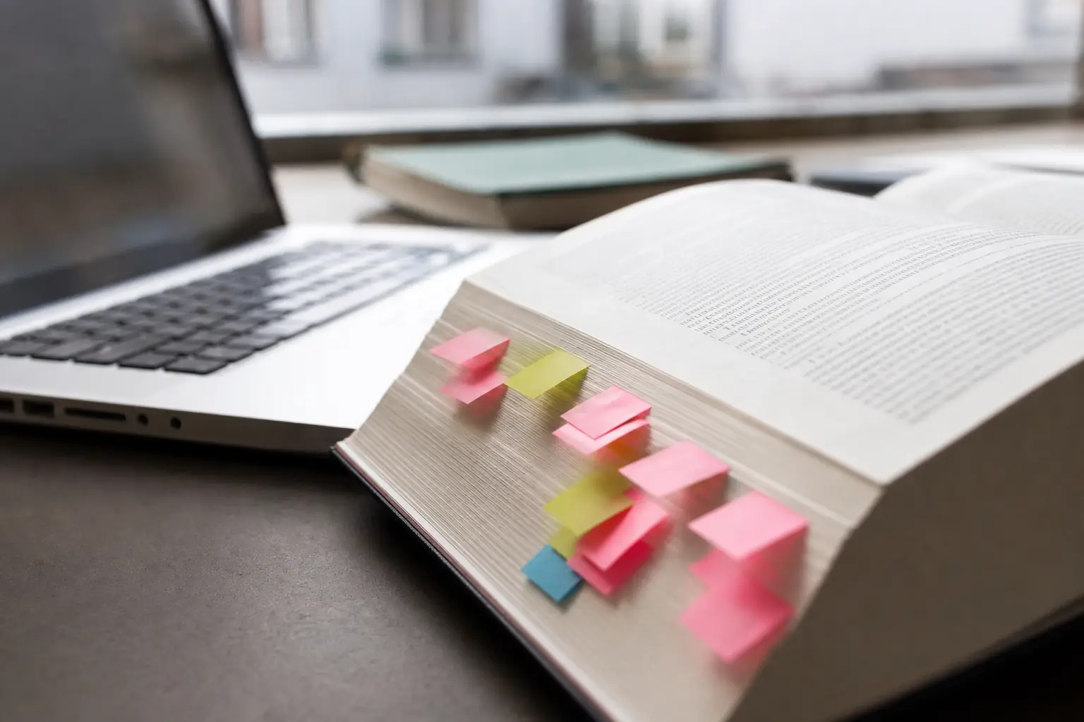 Ouvrage juridique épais ouvert à plat sur un bureau, marque-pages colorés dépassant des pages