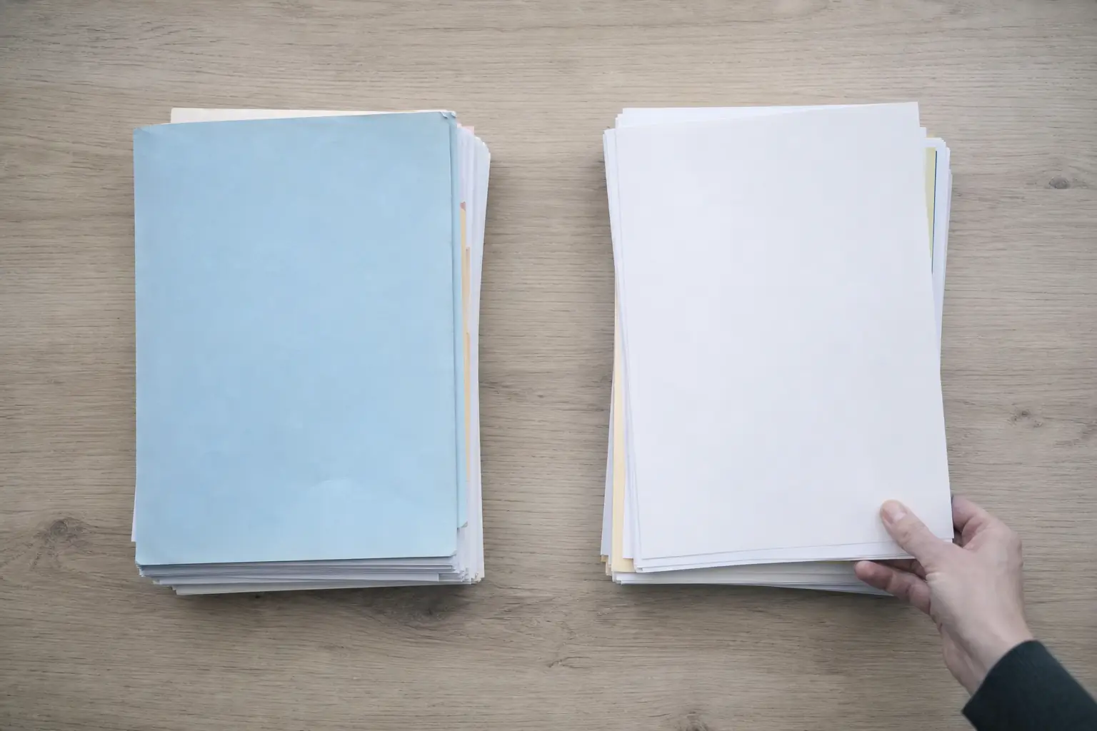 Deux piles de documents posées côte à côte sur une table claire, vues de dessus